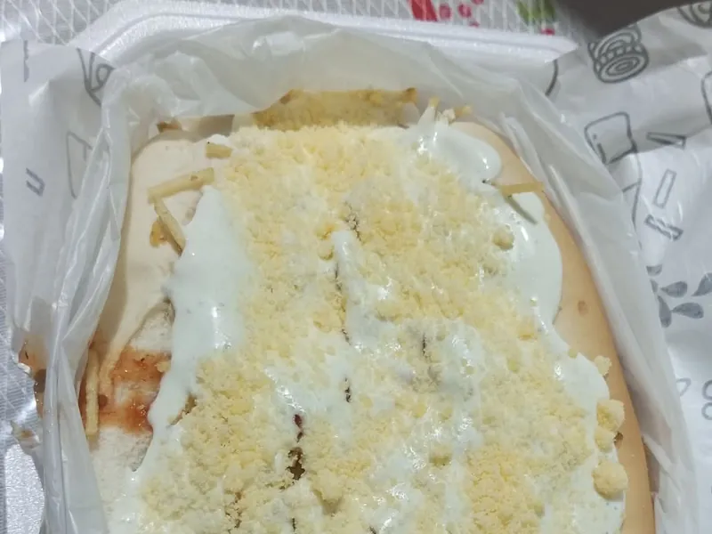 Dog Aberto com maionese e queijo ralado por cima na embalagem de entrega